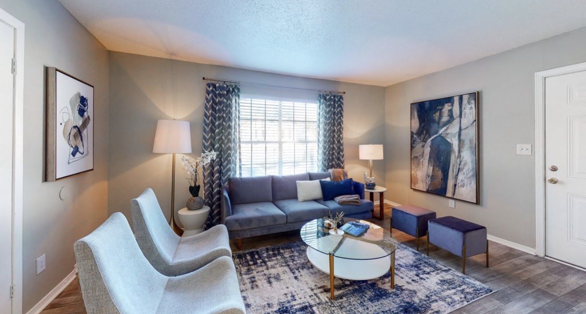 Living room with blue sofa, accent chairs, glass coffee table and framed artwork