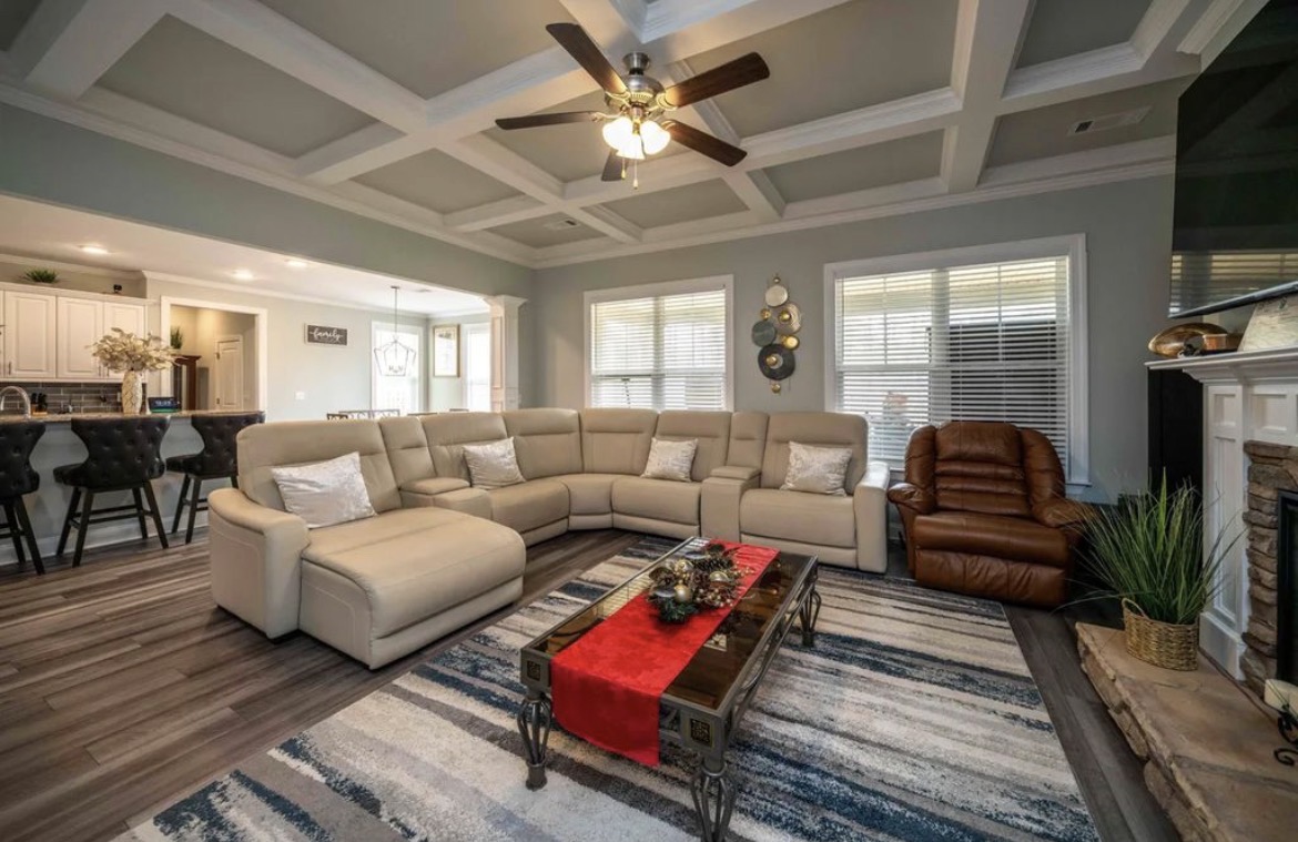 Great room with coffered ceiling, cream leather sectional, fireplace and recliner