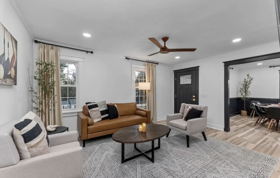 Living room with tan leather sofa, grey armchairs, round wood coffee table and patterned rug